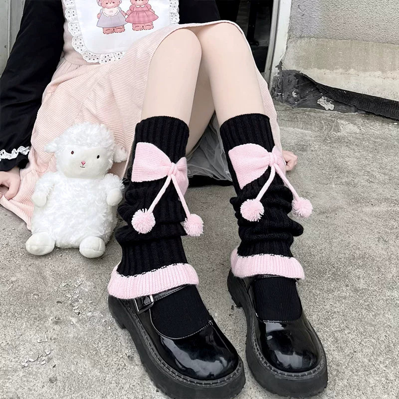 Knit slouch socks with pink bows and pom-poms worn with black Mary Jane shoes.
