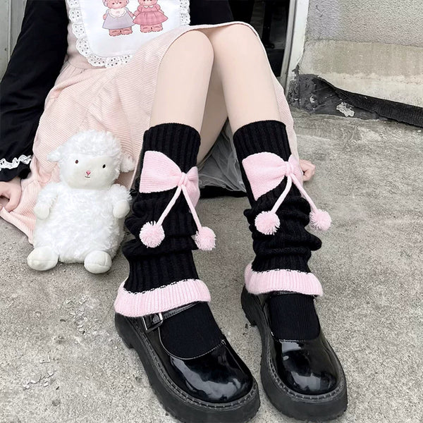 Knit slouch socks with pink bows and pom-poms worn with black Mary Jane shoes.