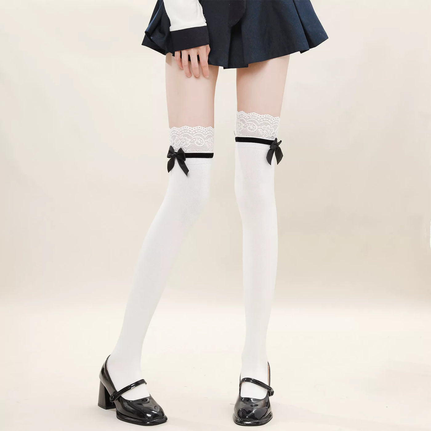 Fantasy Doll white over-the-knee socks with lace tops, black trim and bows styled with a navy skirt.