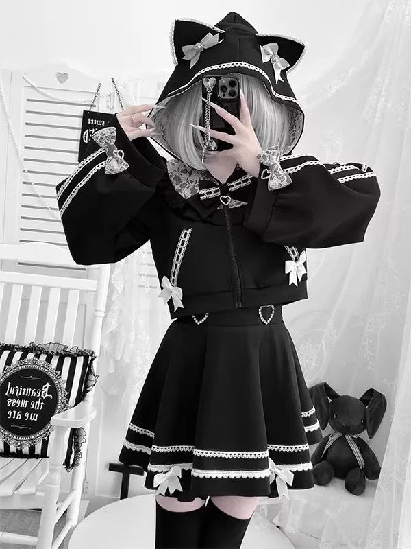 Black cropped jacket and flared skirt set with white bows, trim and cat-ear styling.