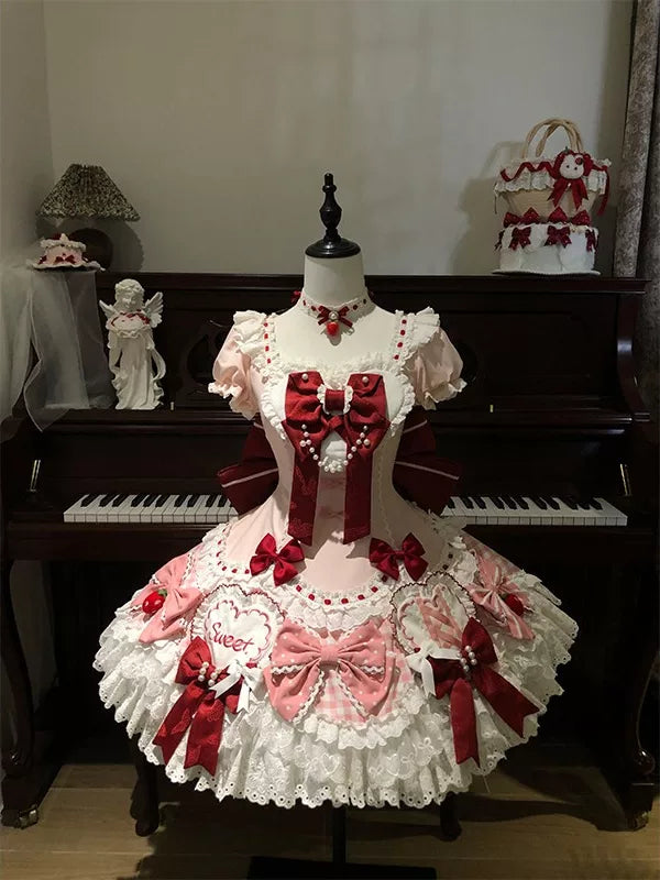 Pink, red and white Strawberry Bunny OP dress displayed on a mannequin with layered lace and bow details.