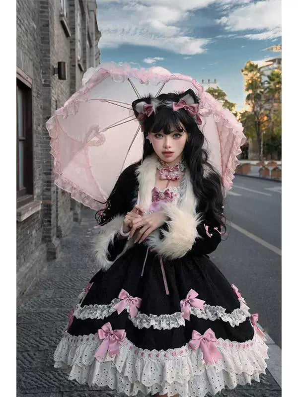 Black JSK dress and coat set with pink ribbon details styled outdoors.