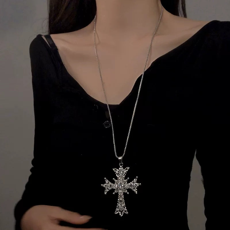 Silver cross pendant necklace worn over black clothing