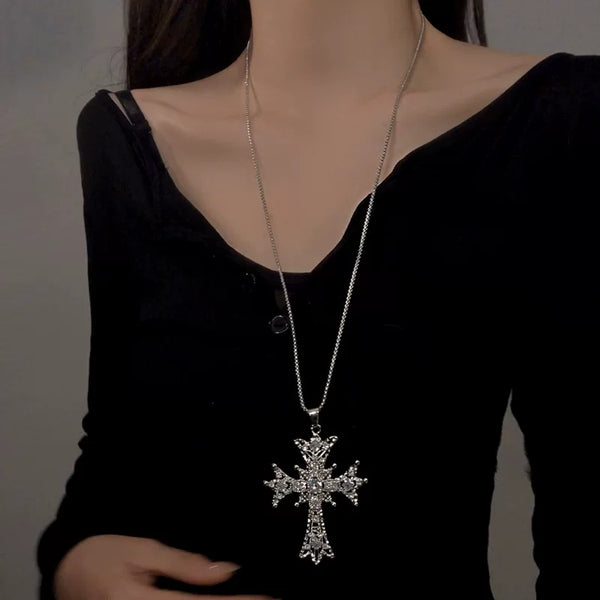 Silver cross pendant necklace worn over black clothing