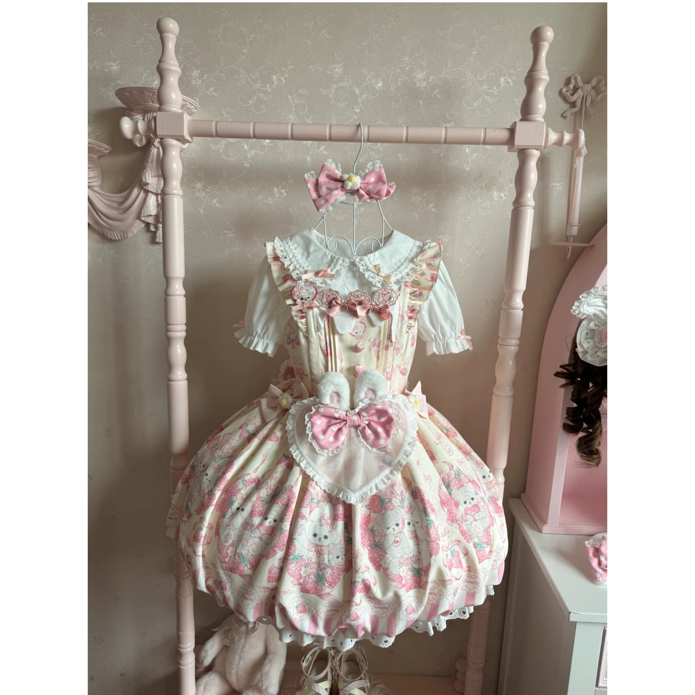 Pink rabbit-and-strawberry JSK dress with a rounded skirt, lace trim and oversized bows worn by a model.