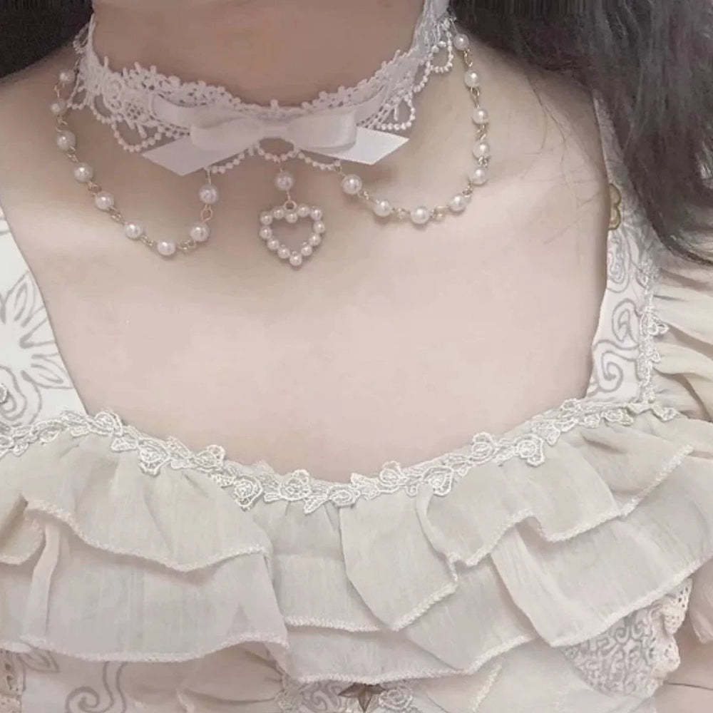Pearl heart collar necklace with lace trim and ribbon bow worn at the neckline.