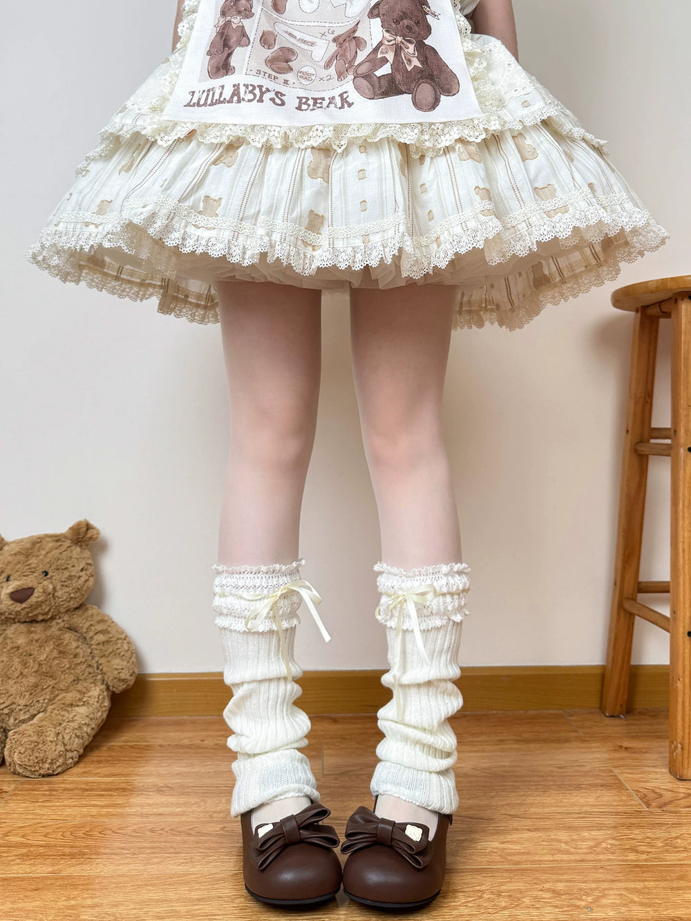 White knit scrunch leg warmers with lace cuffs and pale ribbon ties styled with brown Mary Jane shoes