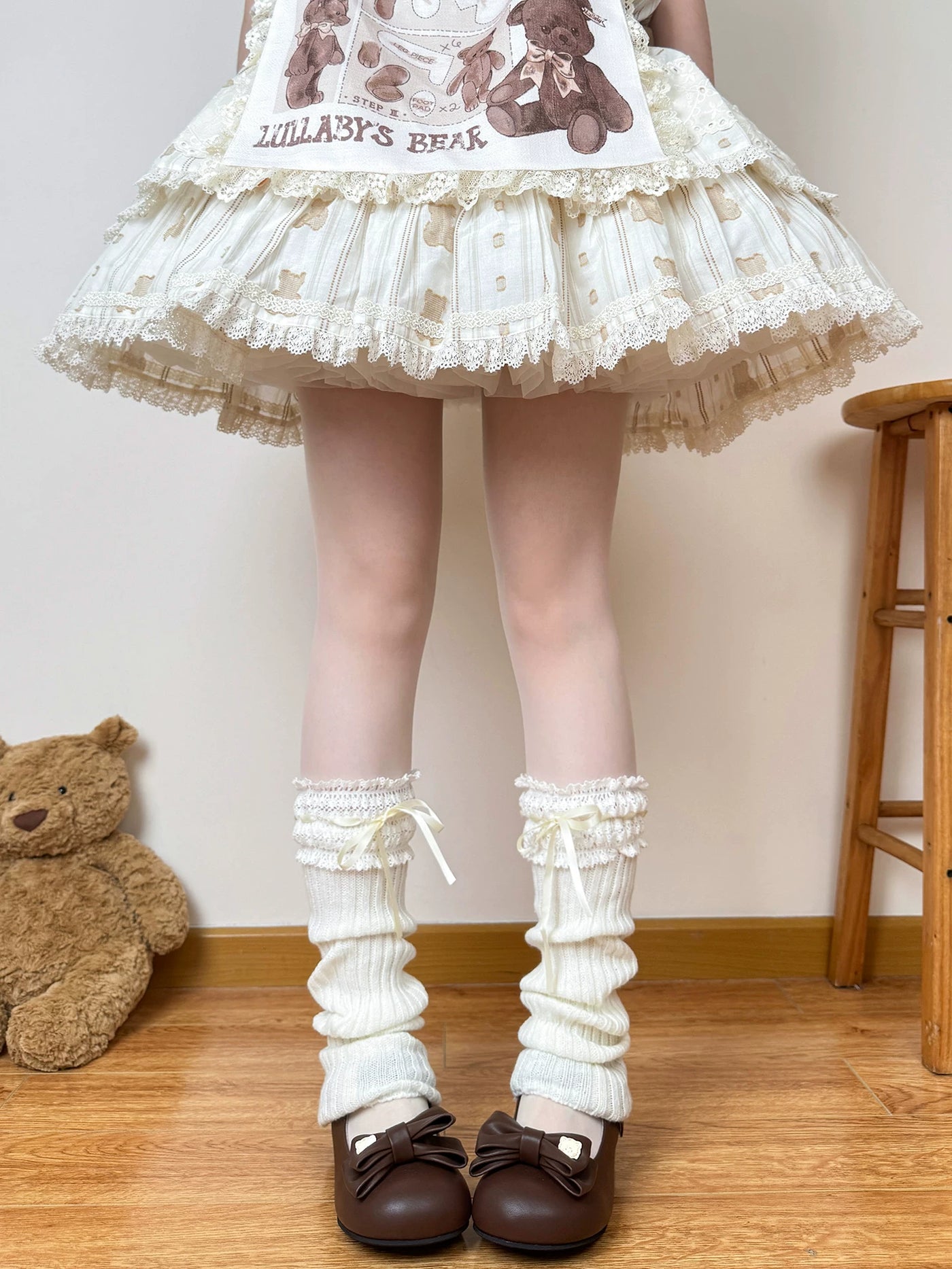 White knit scrunch leg warmers with lace cuffs and pale ribbon ties styled with brown Mary Jane shoes