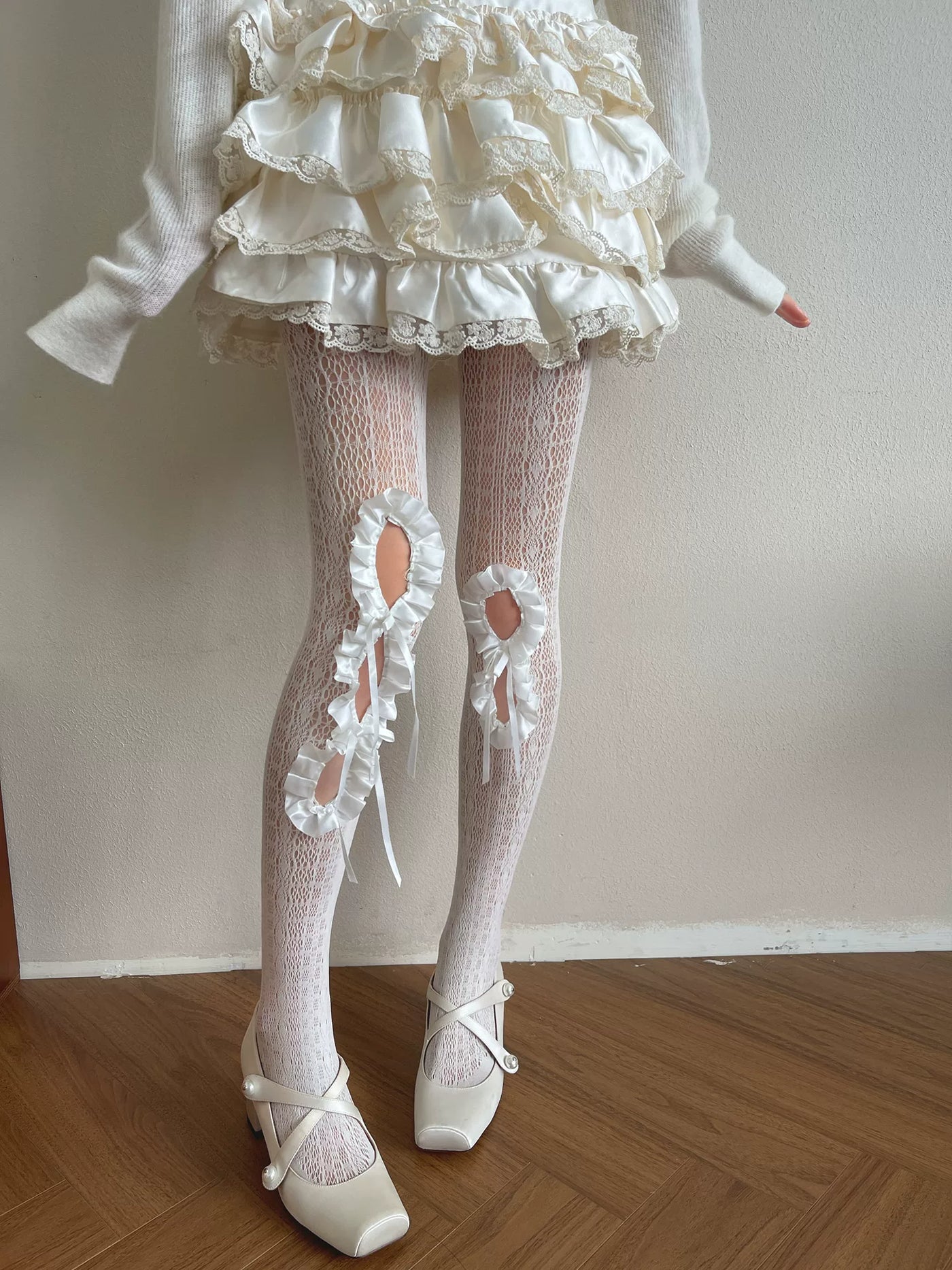 White openwork lace tights with ruffled cutouts and ribbon ties
