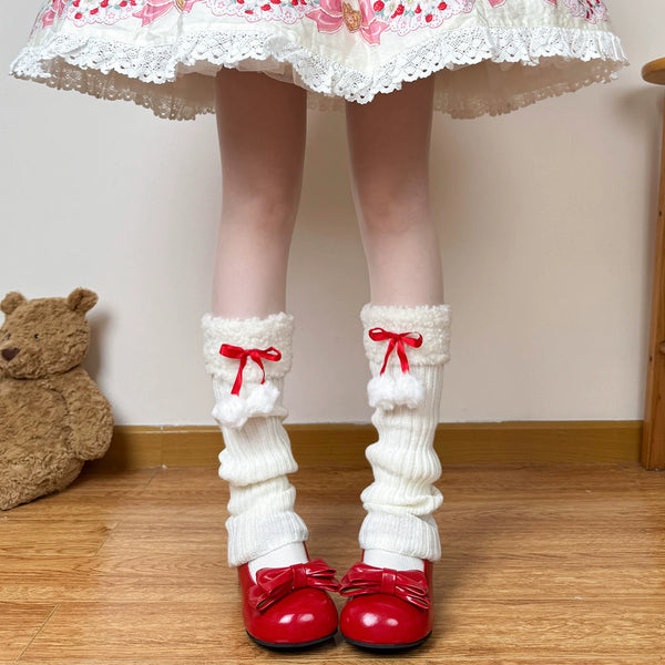 Model wearing off-white scrunched sock covers with red ribbons and white pom-poms.