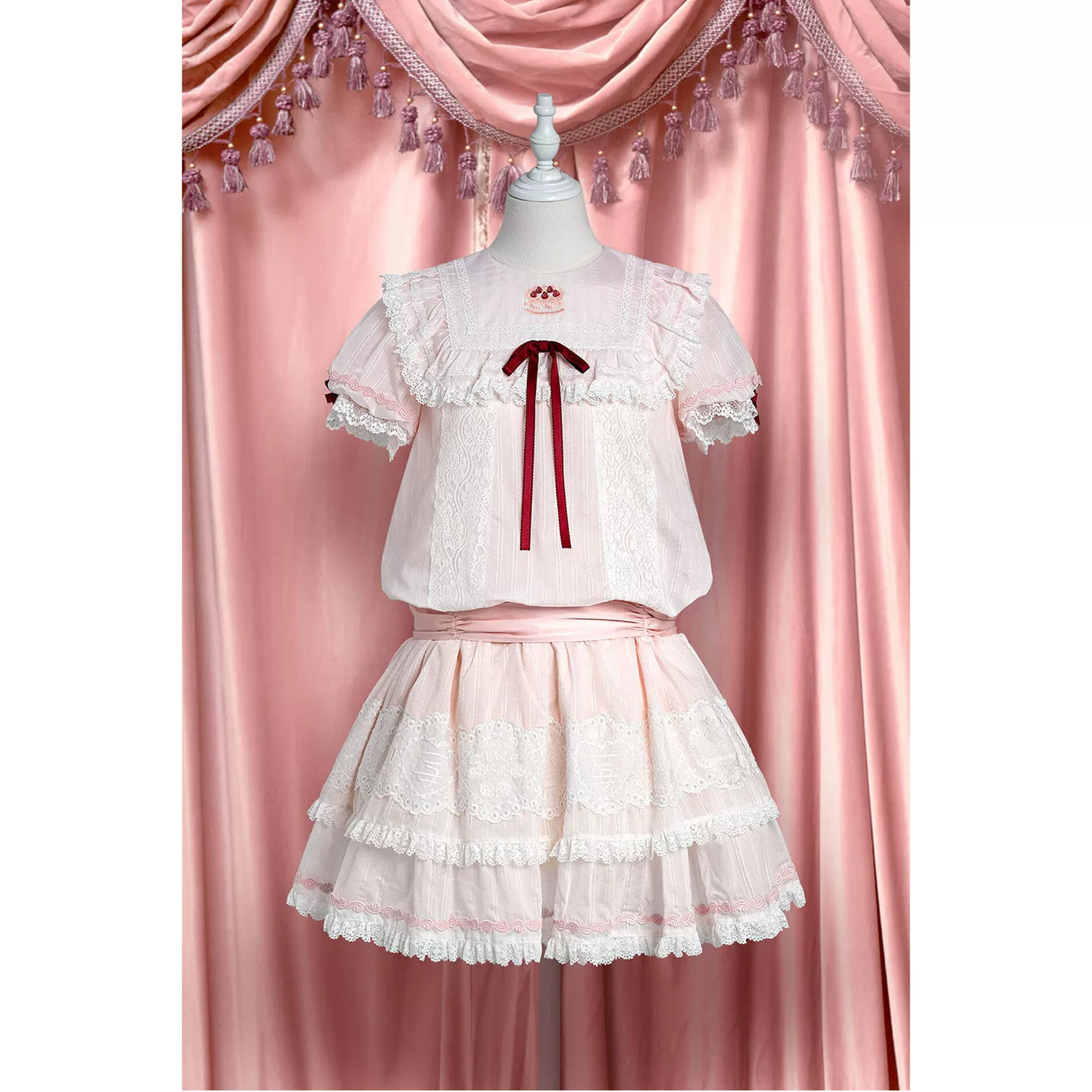 Pink-and-white low-waist one-piece dress with strawberry-themed panels and layered lace tiers.