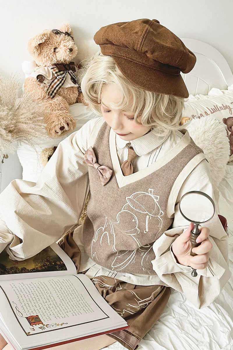 Baozi Pig brown sweater vest with an outlined goose motif, styled over a cream collared blouse.