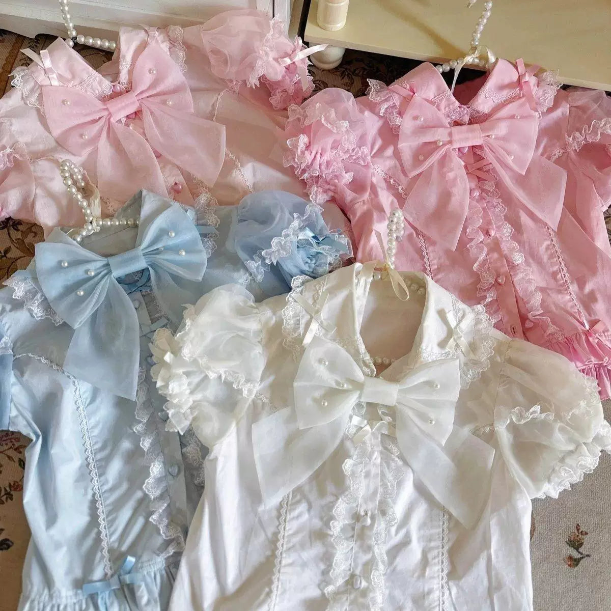 Pink short-sleeve blouse with lace trim and layered bows.