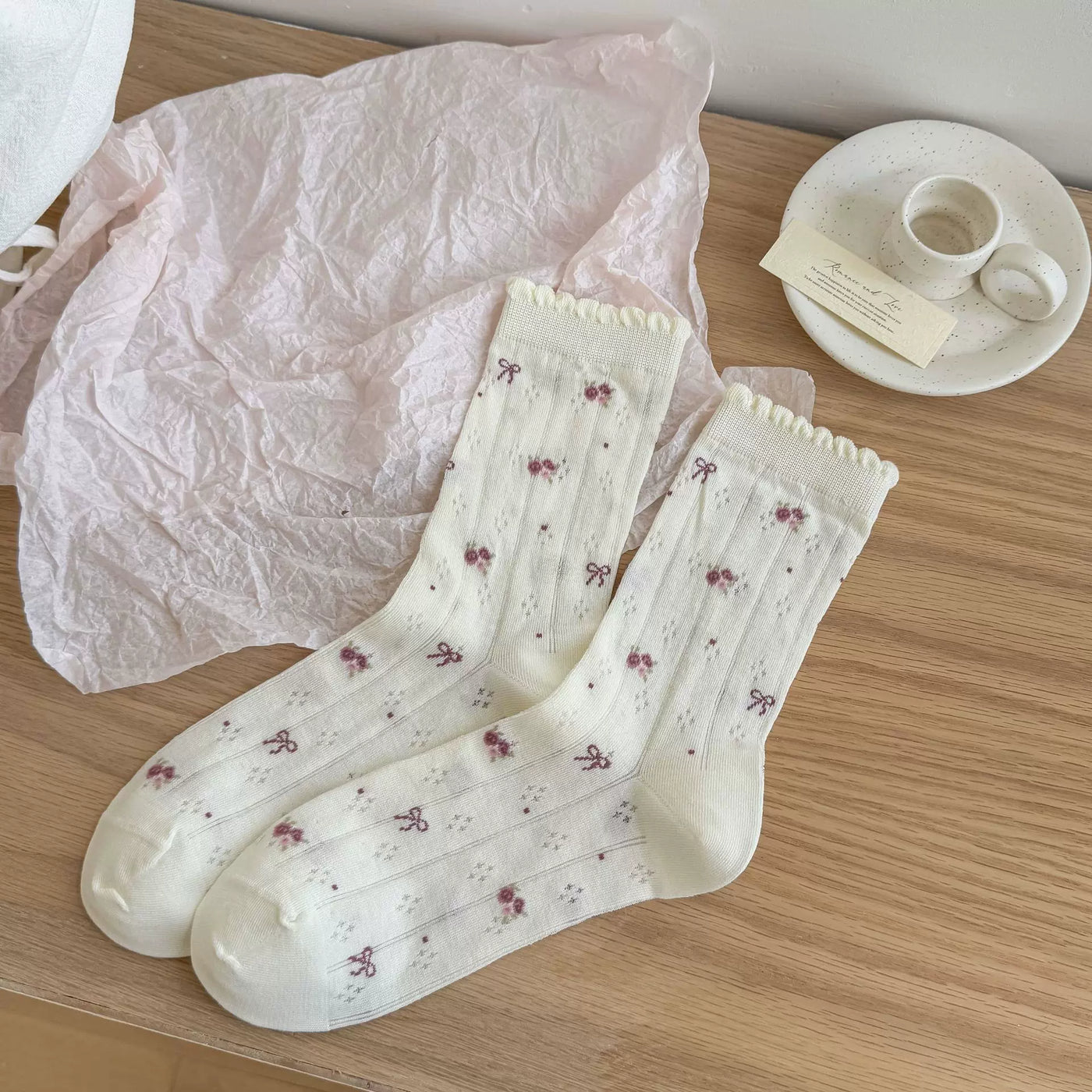 Pink bow and floral-patterned mid-calf socks styled with a pale Lolita outfit