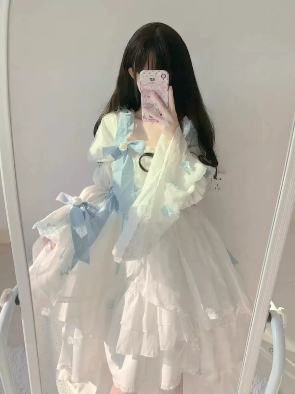 White Lolita one-piece dress with pale blue bows and layered lace ruffles shown in a mirror selfie.