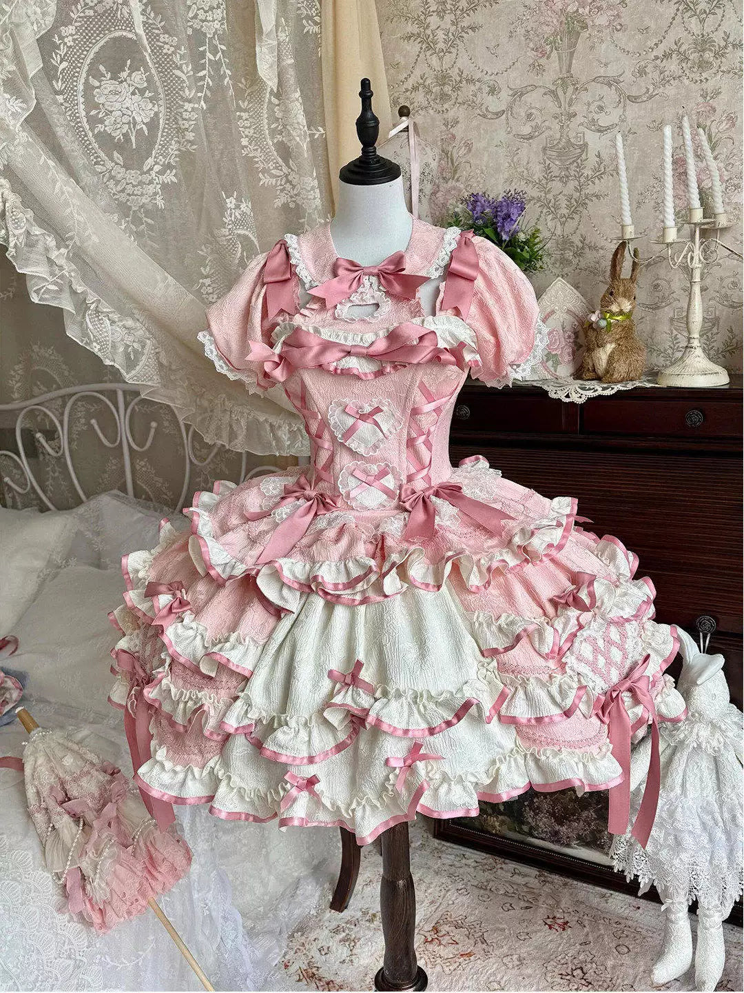 Pink and white ruffled OP dress with bows and a train on a mannequin