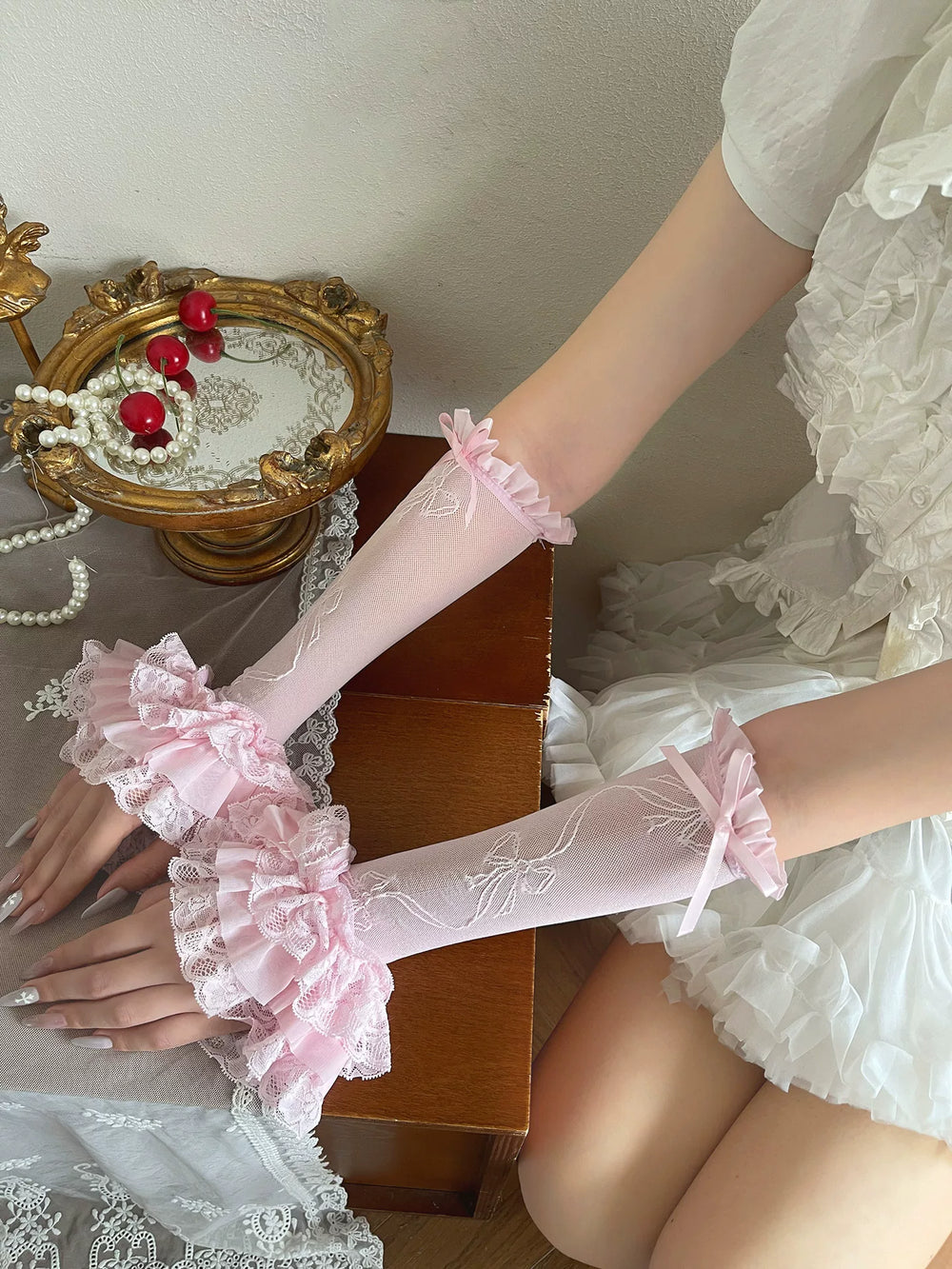 Pink lace sleeve gloves with layered ruffled bow cuffs styled on a model