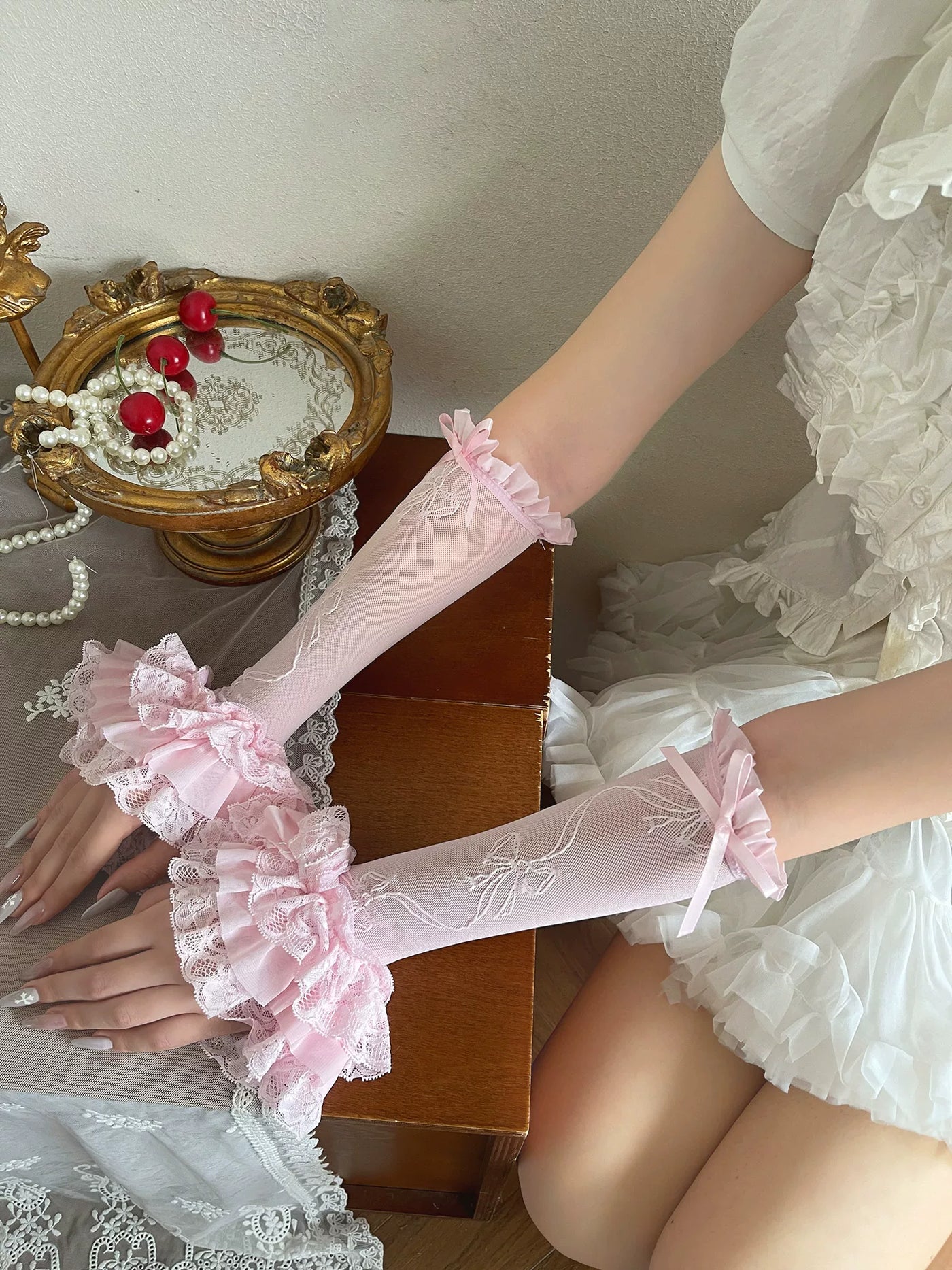 Pink lace sleeve gloves with layered ruffled bow cuffs styled on a model