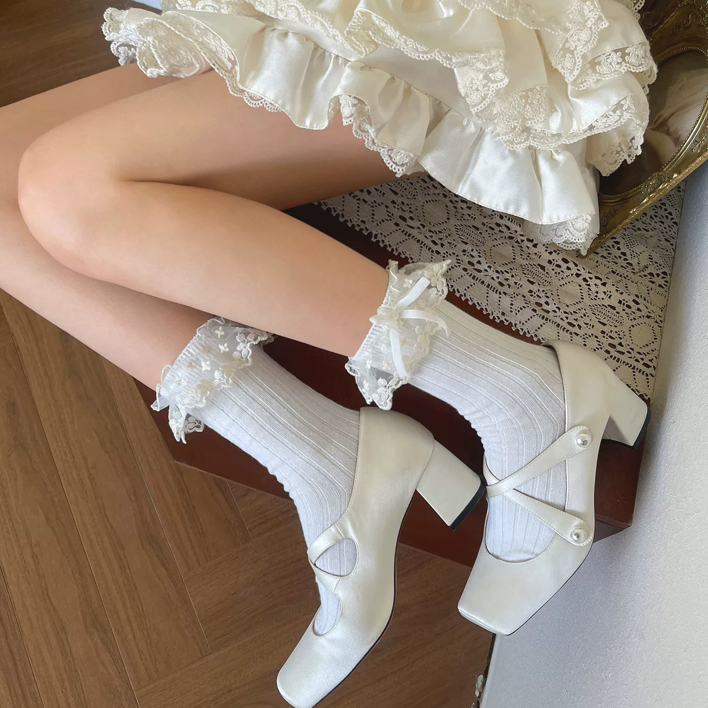 Black slouch socks with embroidered white lace cuffs and bow details styled with glossy black shoes