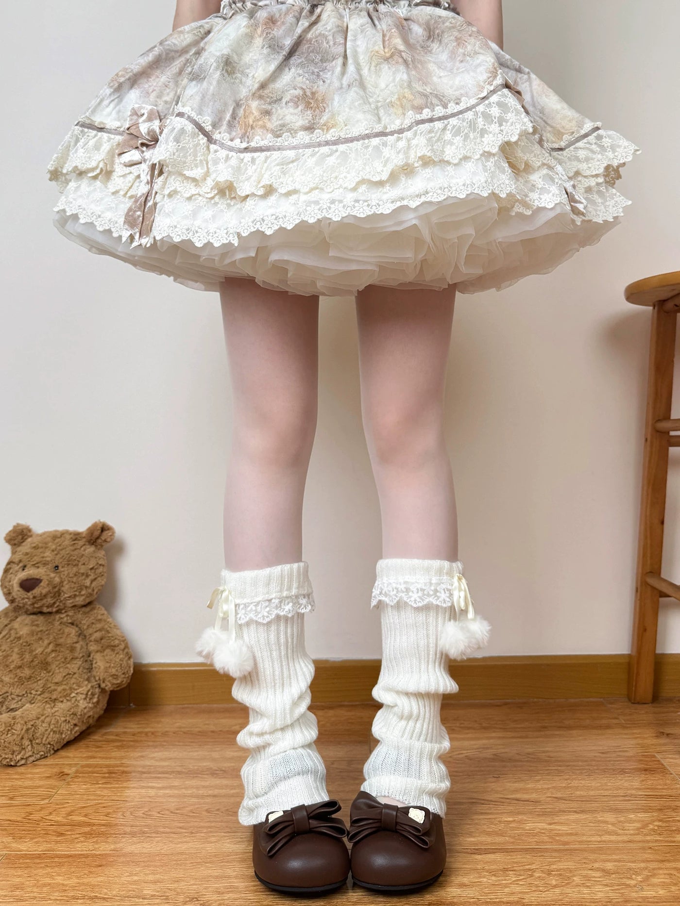White scrunched leg warmers with lace cuffs and pom-pom ties worn with a pale skirt
