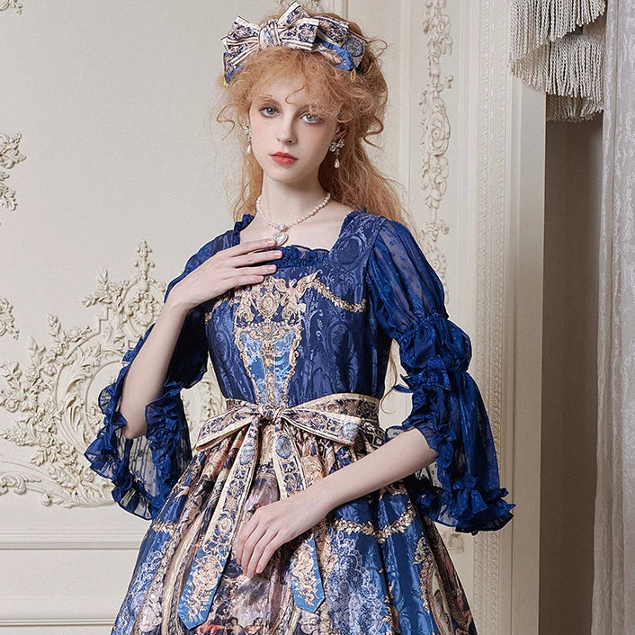 Model wearing the Krad Lanrete Echoes of Versailles JSK in dark blue with ornate print and a wide waist bow.