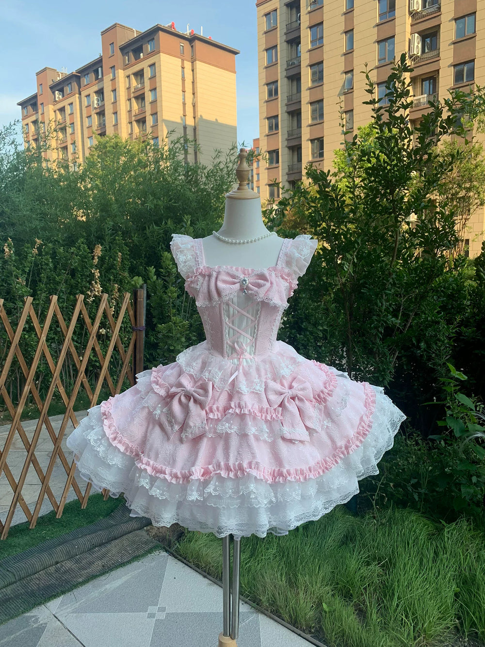 Pink ruffled JSK with train and waist bow displayed on a mannequin.