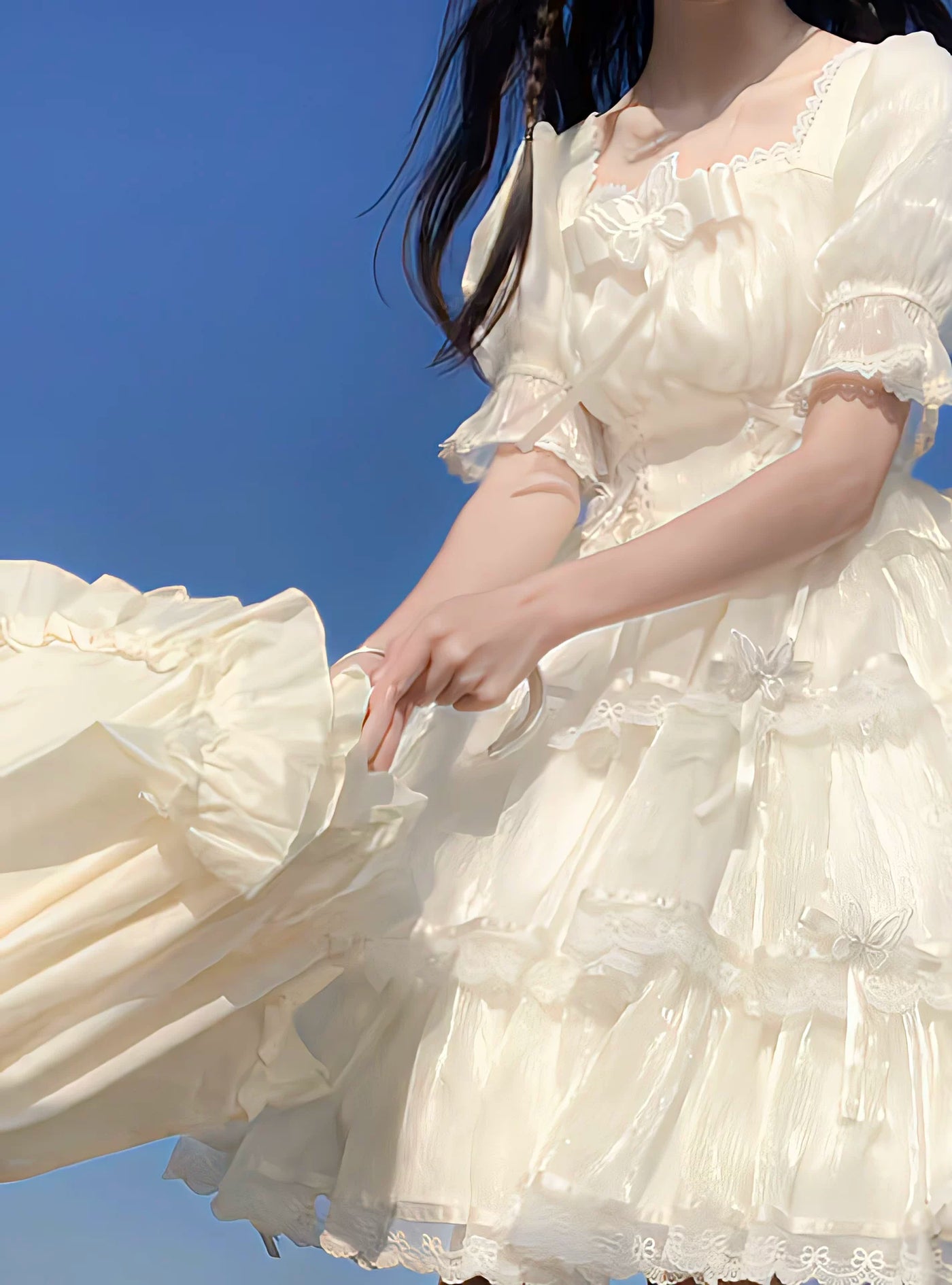 Natural-tone OP dress with tiered lace skirt and train, photographed beside the sea.