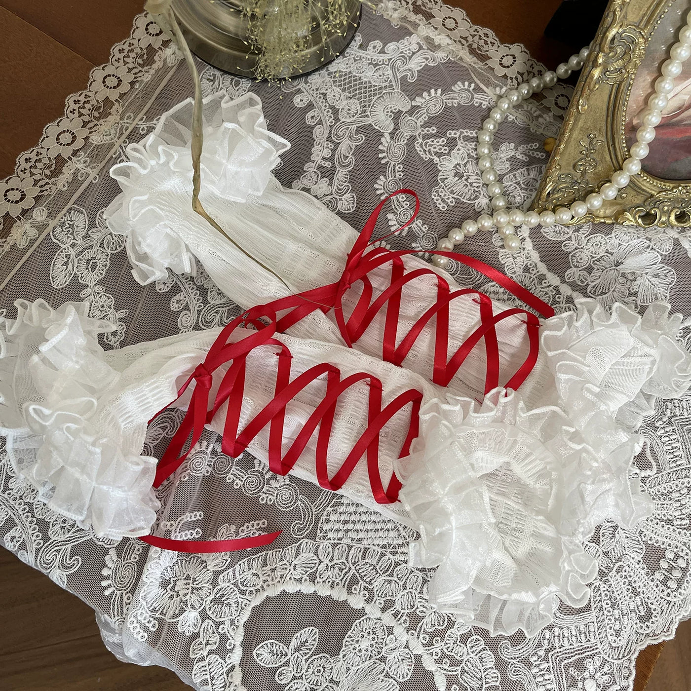 White mesh arm sleeves with ruffled cuffs and contrasting ribbon ties styled on a model.