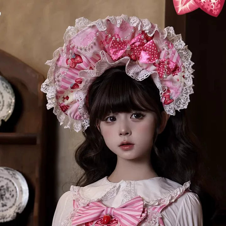 Pink strawberry-print Lolita dress with striped bows, lace trim and a matching bonnet.