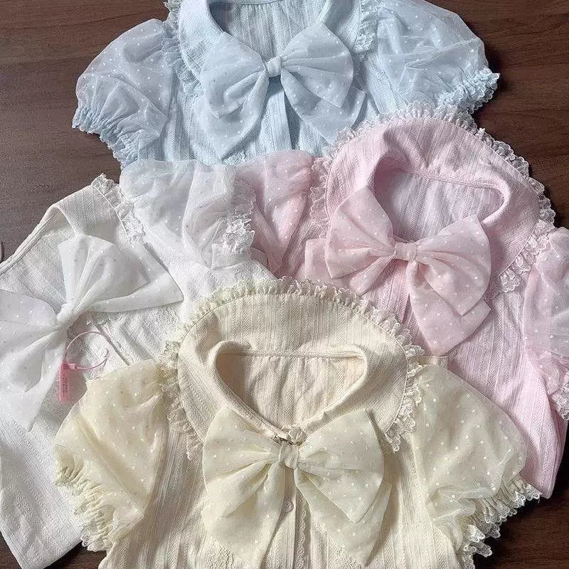 Close-up of a pink-and-white lace inner blouse styled with a separate large bow.