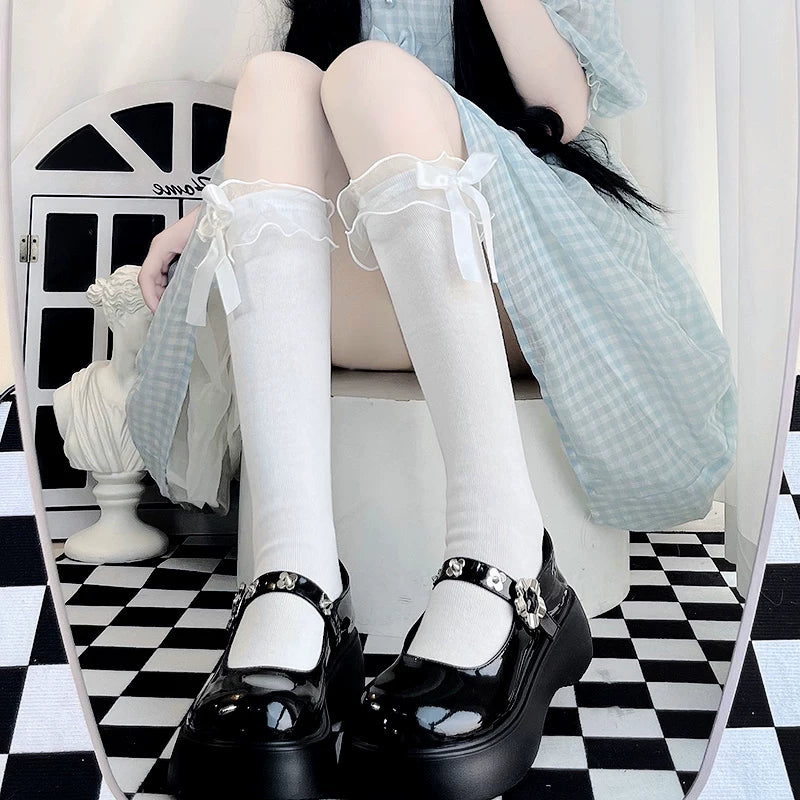 Floral Milk Cat white bow-trimmed knee-high socks styled with black platform Mary Jane shoes.