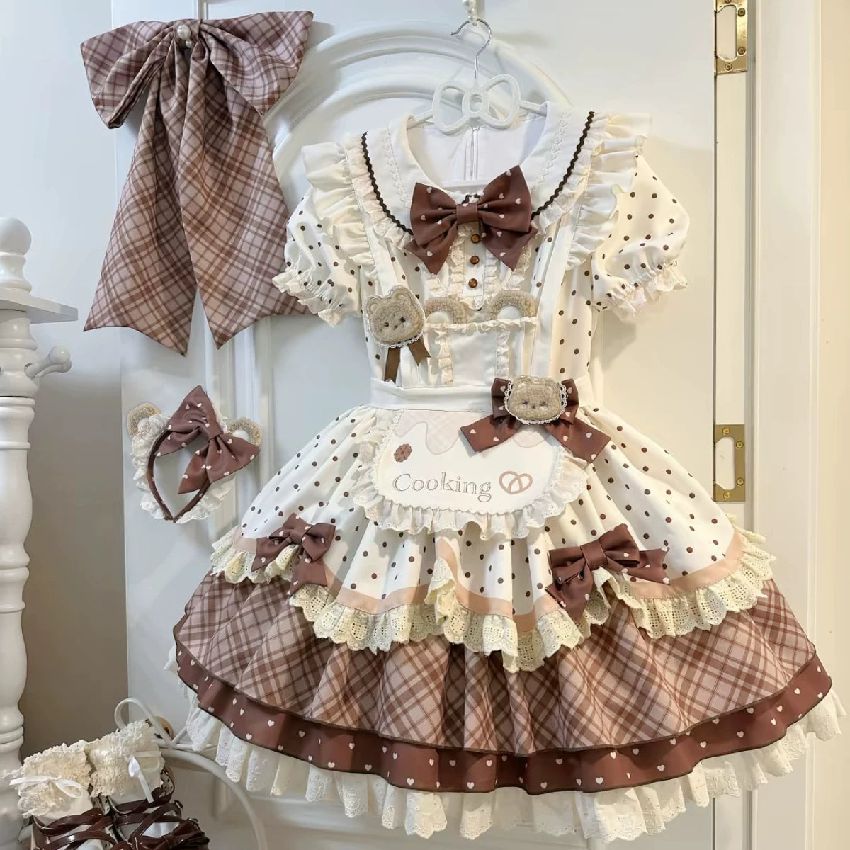 Hanging cream-and-brown one-piece dress with polka dots, lace ruffles, bear accents and visible bows.