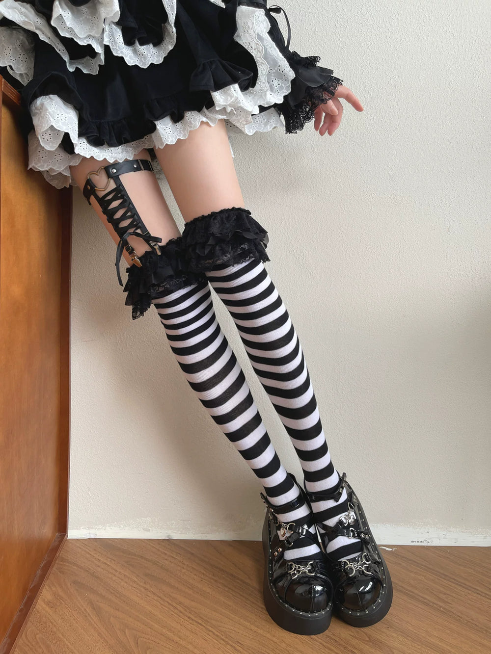 Black-and-white striped over-the-knee socks with black lace trim and a clip ring styled on a model.