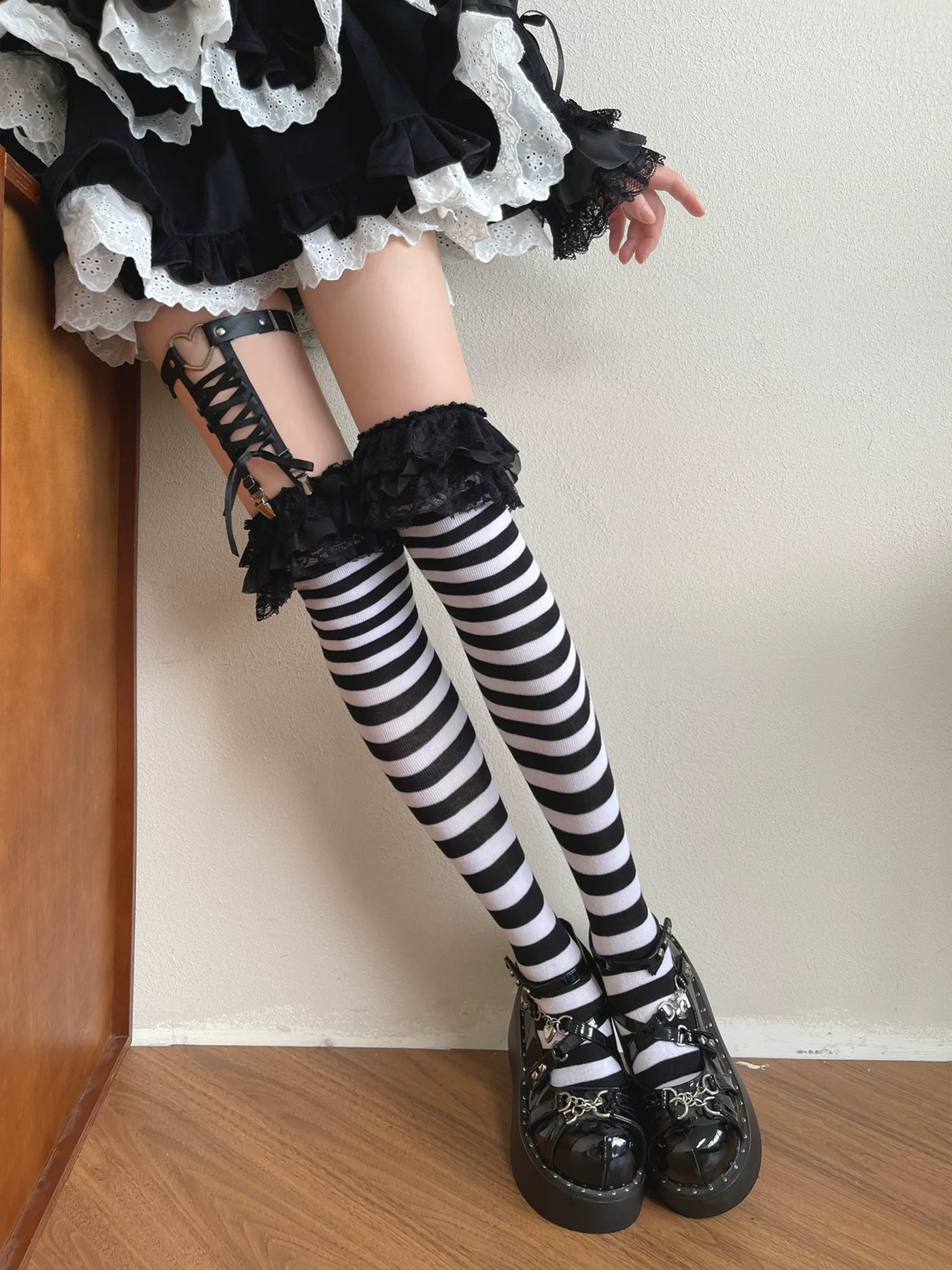 Black-and-white striped over-the-knee socks with black lace trim and a clip ring styled on a model.