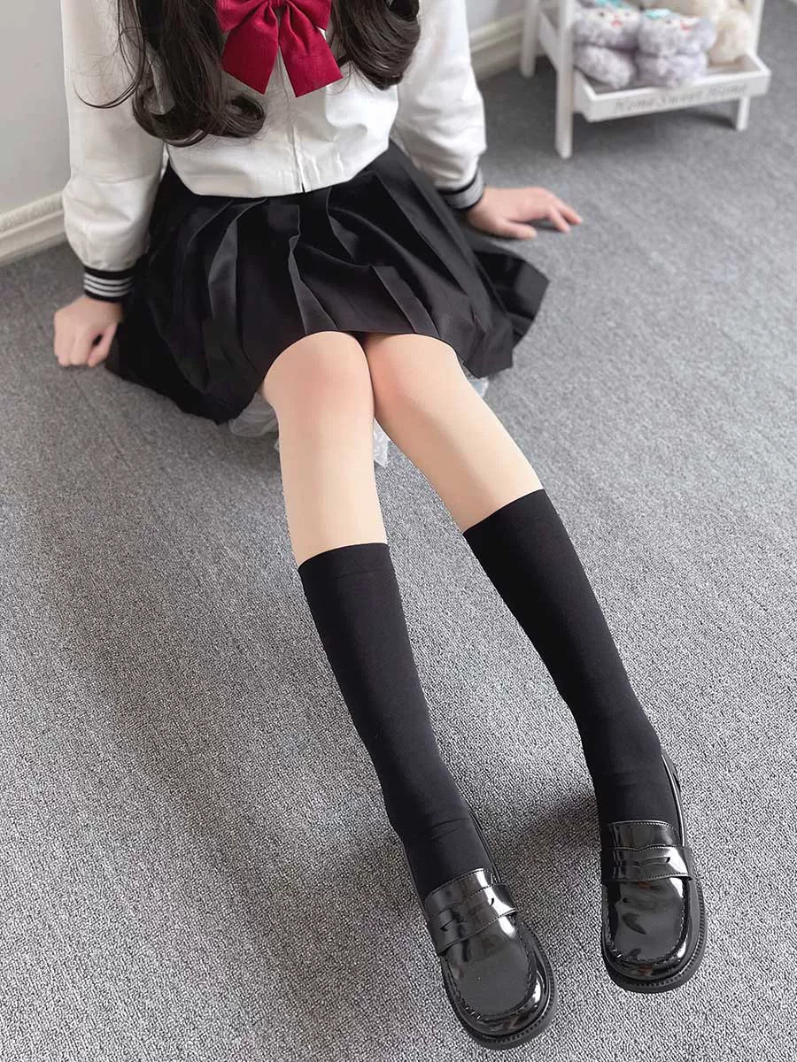 Black over-the-knee socks worn with a sailor-style skirt and glossy loafers