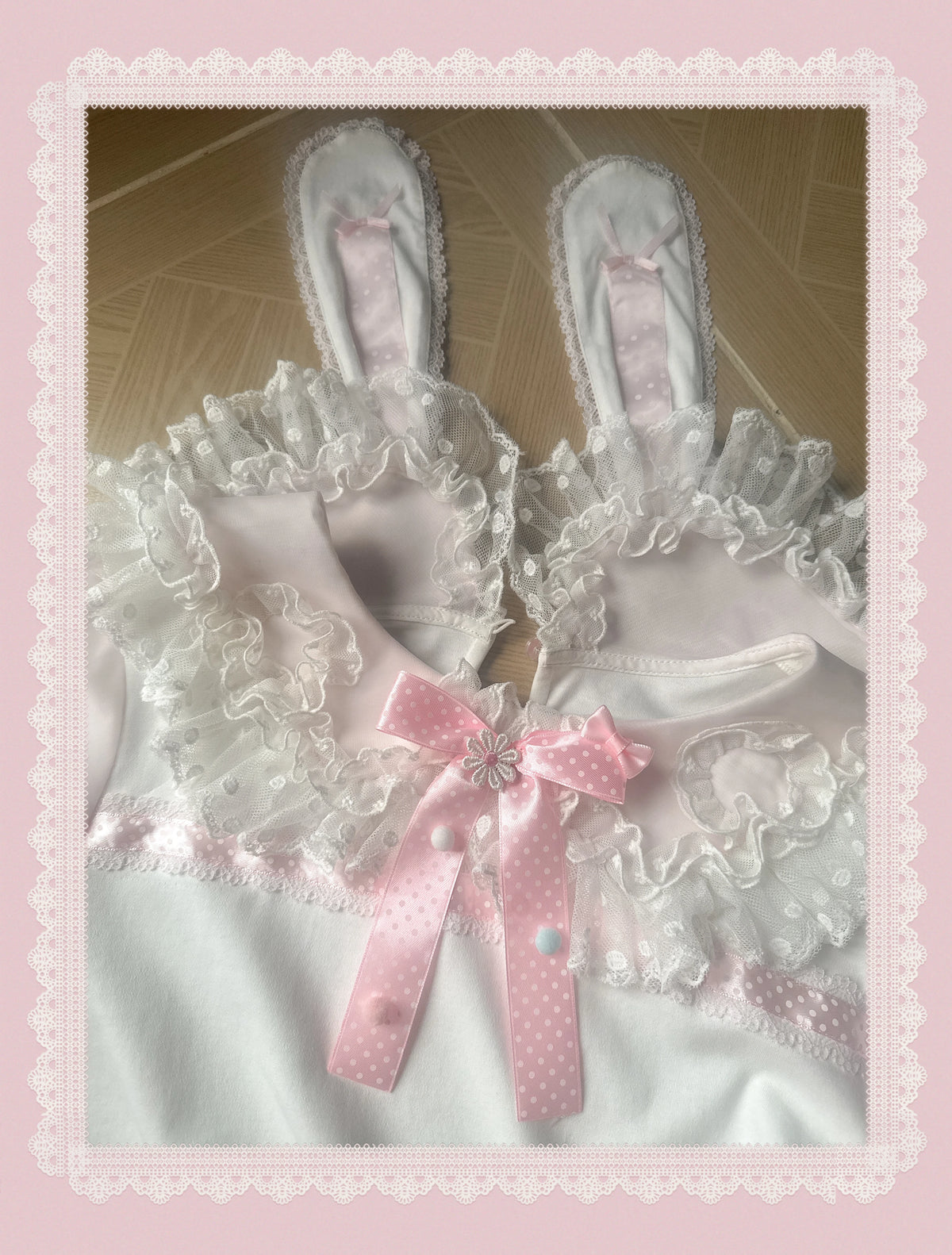 Pink Lolita apron with layered white lace, ruffles and a polka-dot bow, shown flat.