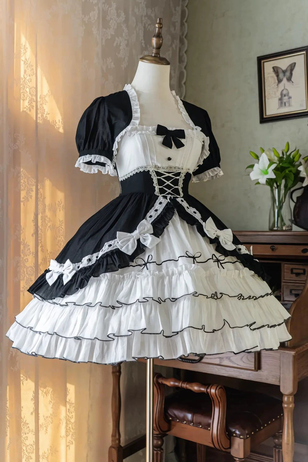 Black-and-white tiered JSK dress with bows and a short sleeveless jacket displayed on a mannequin.