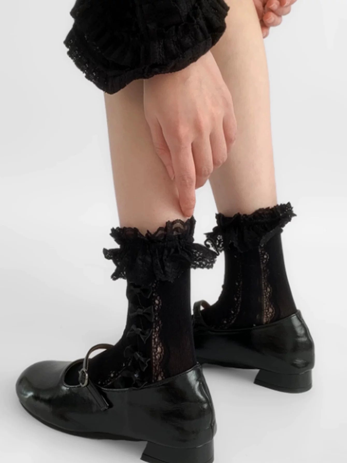 Lace-panel mid-calf socks with repeated bows and ruffled edging styled on a model.