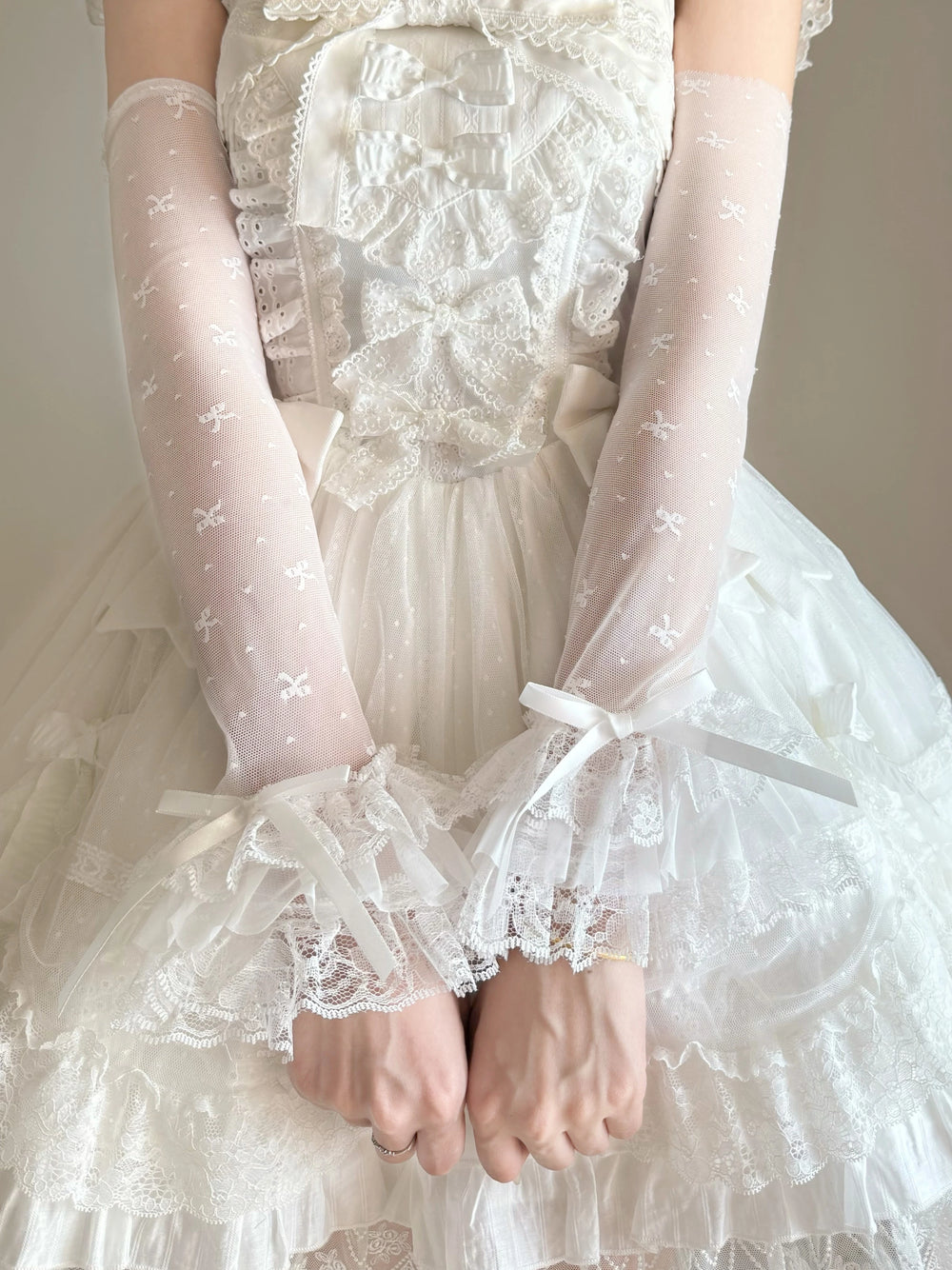 White lace-trim arm sleeves with small bow motifs
