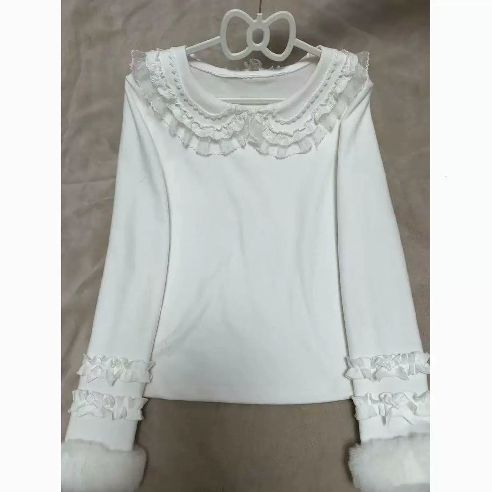 White long-sleeve top with a layered Peter Pan collar and ruffled cuffs hanging on a hanger.