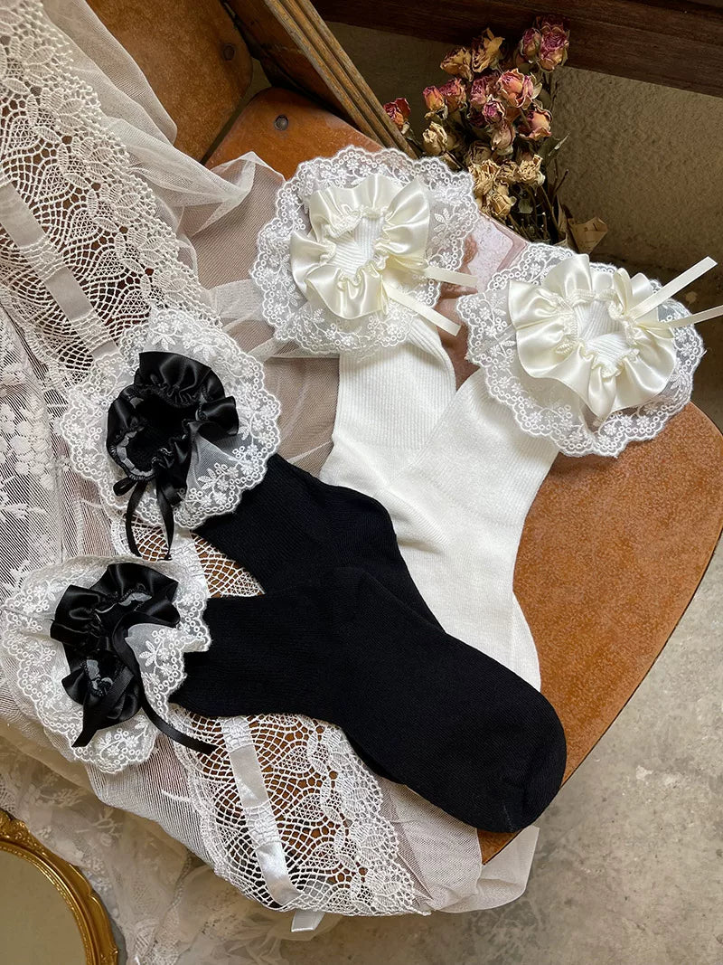 White and black mid-calf socks with layered lace ruffle cuffs and satin bows.