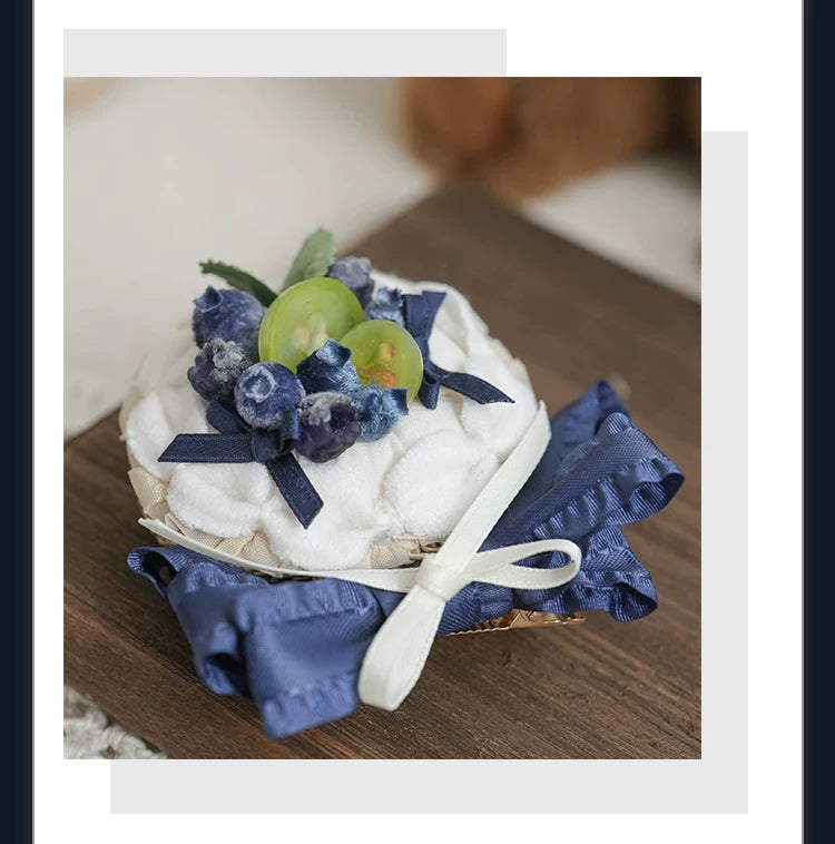 Blueberry-and-cream tart hat with navy ribbon accents.