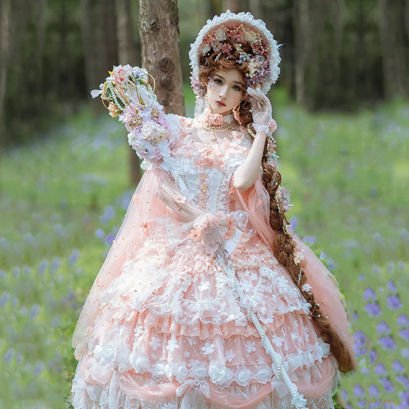 Model wearing pale peach sweet lolita bridal JSK with tiered ruffled skirt, floral appliqués, and wide-brimmed bonnet