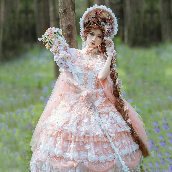 Model wearing pale peach sweet lolita bridal JSK with tiered ruffled skirt, floral appliqués, and wide-brimmed bonnet