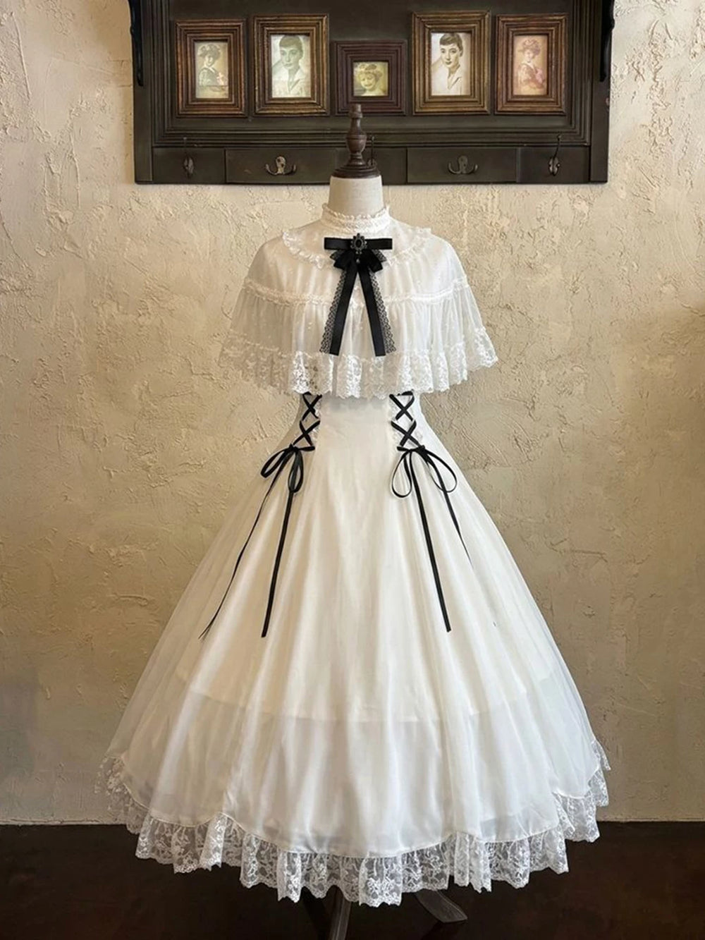 White full-length OP dress on a mannequin with black ribbon lacing and a lace hem.