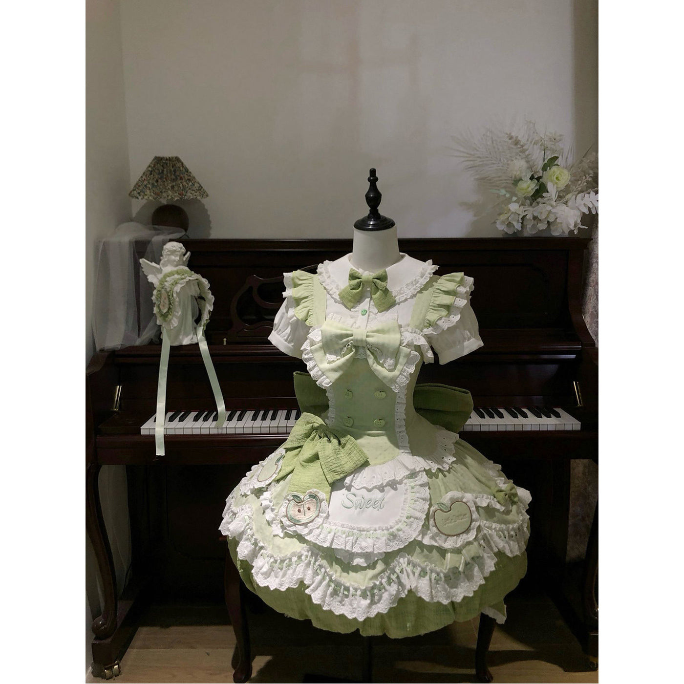 Green and white apple-themed dress set on a dress form.