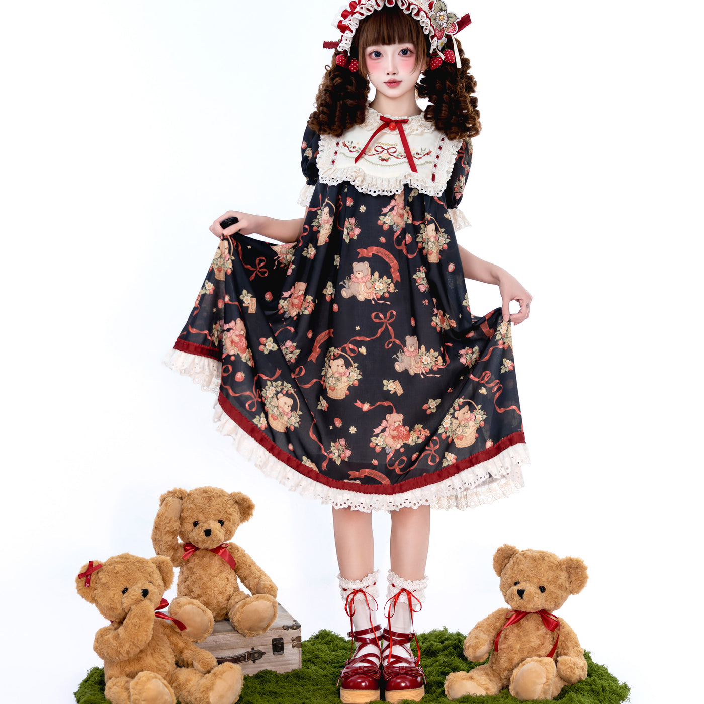 Model views of a printed OP dress with teddy bears, strawberries and ribbons in dark and off-white colourways.