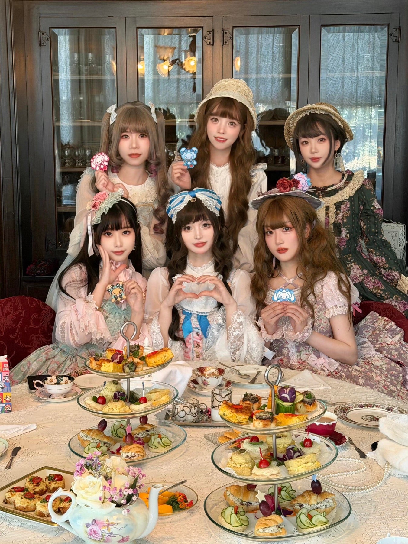 A group of Lolita fashion guests gathered around an afternoon tea table.