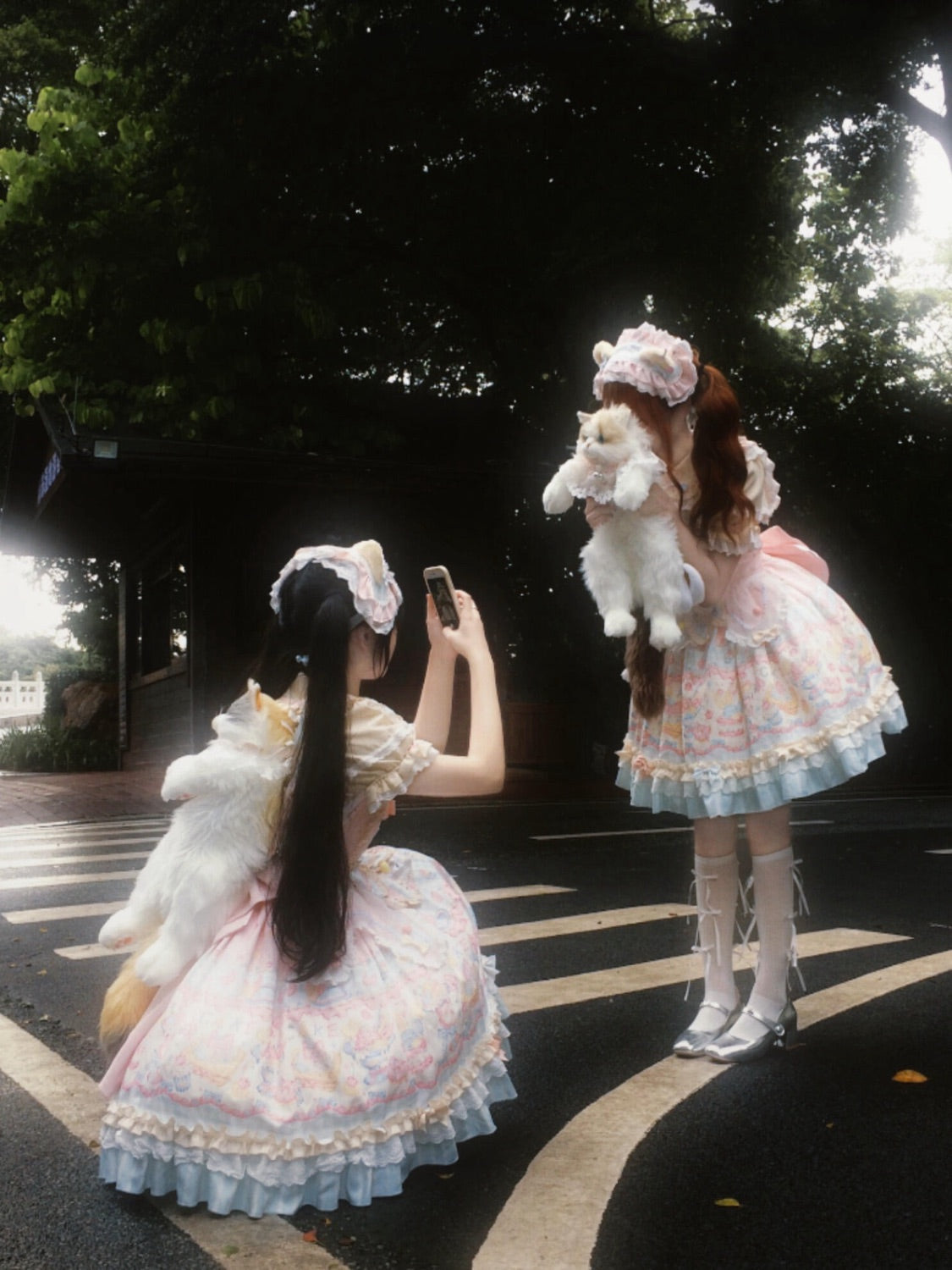 Two Lolita fashion guests taking photos of one another outdoors.