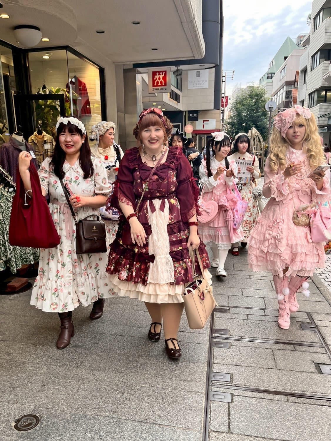 Lolita fashion guests walking together through a city street.